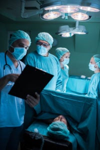 Doctors reading medical documents of a patient before the surgery. Focus is on doctor with glasses.