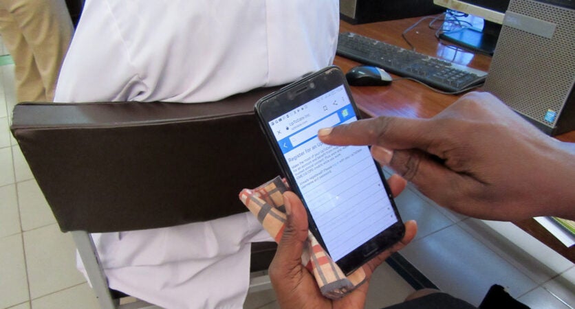 A woman holds a cellphone with UpToDate on the screen.