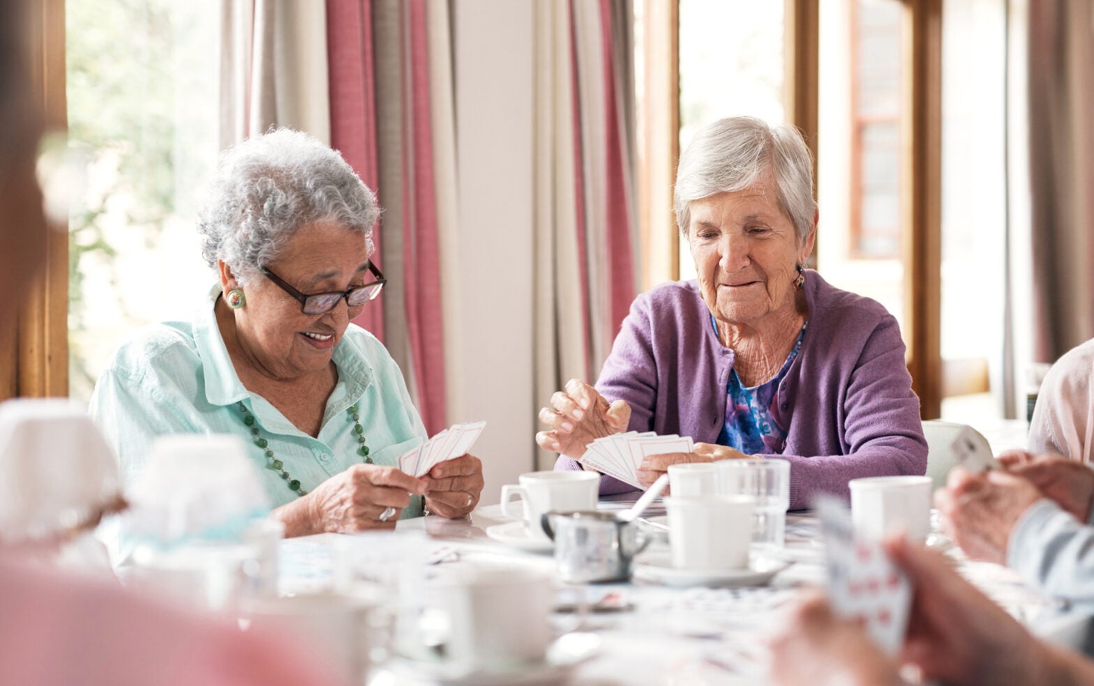 Elderly nursing home residents play cards at a table